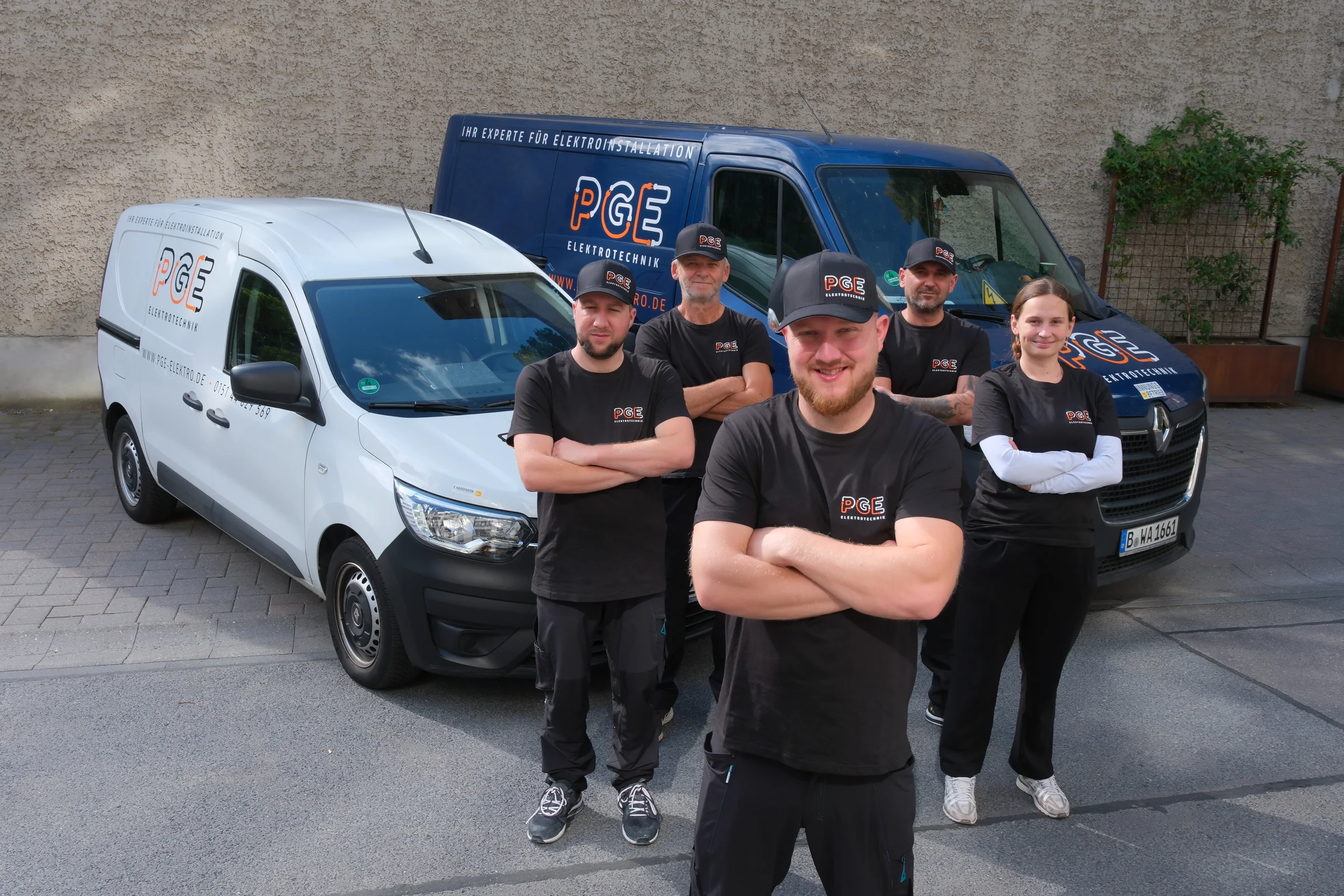 Das Team von PGE Elektrotechnik vor zwei Firmenfahrzeugen, mit Piotr im Vordergrund